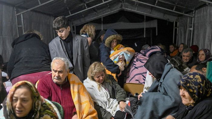 EDITORS NOTE: Graphic content / Earthquake survivors sit sheltering in a tent in Hatay, the day after a 7.8-magnitude earthquake struck the country's southeast on February 7, 2023. - Rescuers in Turkey and Syria braved frigid weather, aftershocks and collapsing buildings, as they dug for survivors buried by an earthquake that killed more than 5,000 people. Up to 23 million people could be affected by the massive earthquake that has killed thousands in Turkey and Syria, the WHO warned on Tuesday, promising long-term assistance. (Photo by BULENT KILIC / AFP)