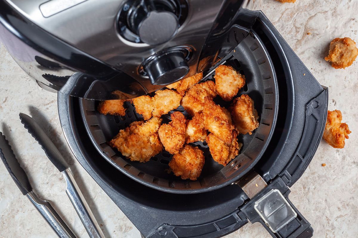 Close,Up,Flat,Lay,Image,Of,An,Air,Fryer,OvenClose up flat lay image of an air fryer oven on kitchen countertop. This offers fast and easy crispy food with little or no fat by circulating hot air inside the basket. A healthy snack alternative.
