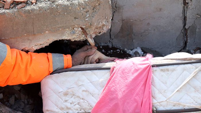 Mesut Hancer holds the hand of his 15-year-old daughter Irmak, who died in the earthquake in Kahramanmaras, close to the quake's epicentre, the day after a 7.8-magnitude earthquake struck the country's southeast, on February 7, 2023. - Rescuers in Turkey and Syria braved frigid weather, aftershocks and collapsing buildings, as they dug for survivors buried by an earthquake that killed more than 5,000 people. Some of the heaviest devastation occurred near the quake's epicentre between Kahramanmaras and Gaziantep, a city of two million where entire blocks now lie in ruins under gathering snow. (Photo by Adem ALTAN / AFP)
