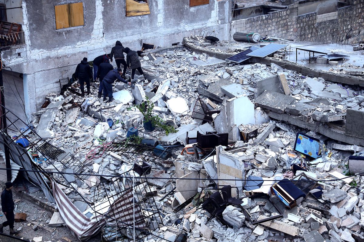 Residents search for victims and survivors amidst the rubble of a building that collapsed, following an earthquake in the village of Azmarin, near the Turkish border in the north of Syria's rebel-held northwestern Idlib province, early on February 6, 2023. - At least 100 have been reportedly killed in north Syria after a 7.8-magnitude earthquake that originated in Turkey and was felt across neighbouring countries. (Photo by OMAR HAJ KADOUR / AFP)