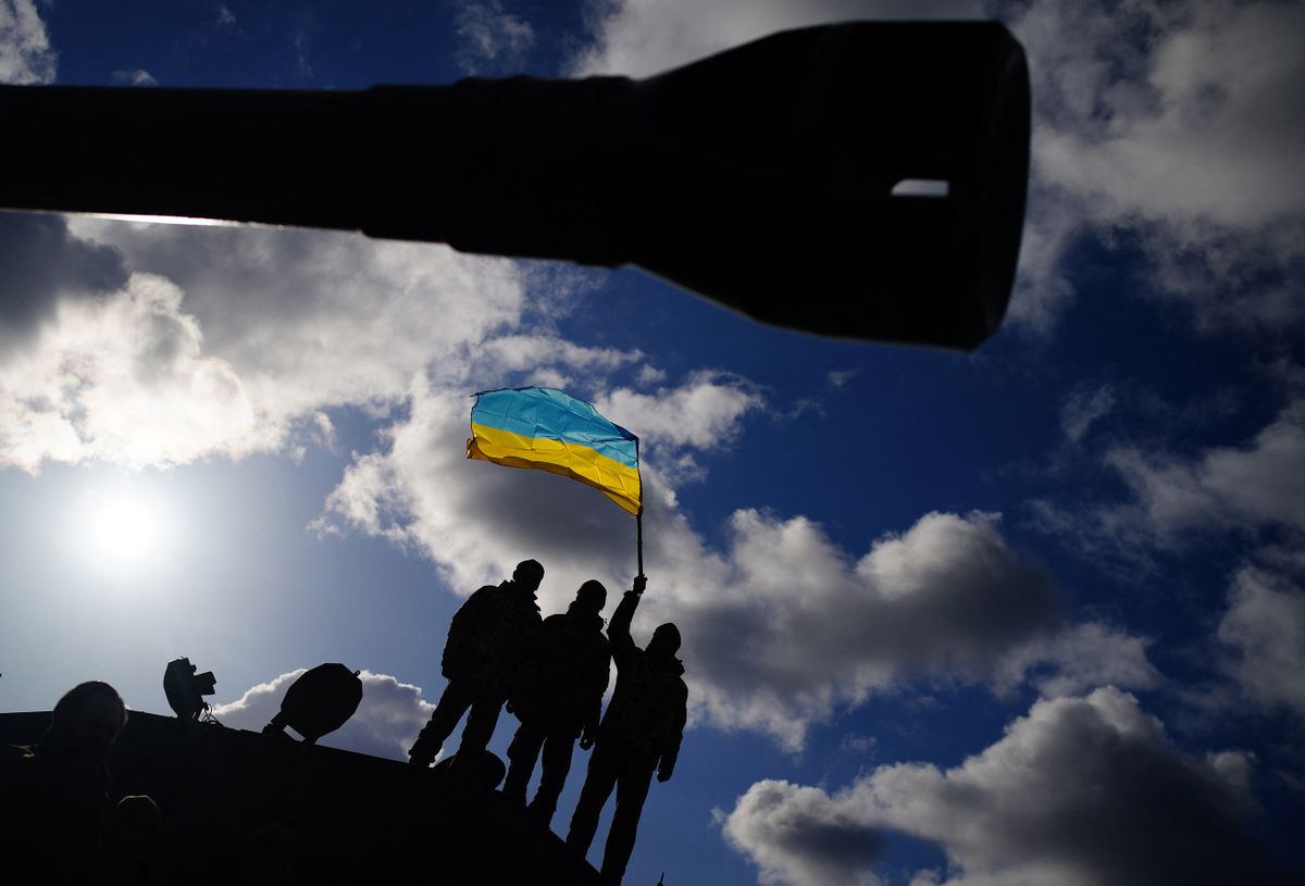 Ukrainian soldiers who are undergoing training at Bovington Camp, a British Army military base, wave a Ukrainian flag, during a visit by Defence Secretary Ben Wallace (unseen), southwest England, on February 22, 2023. 