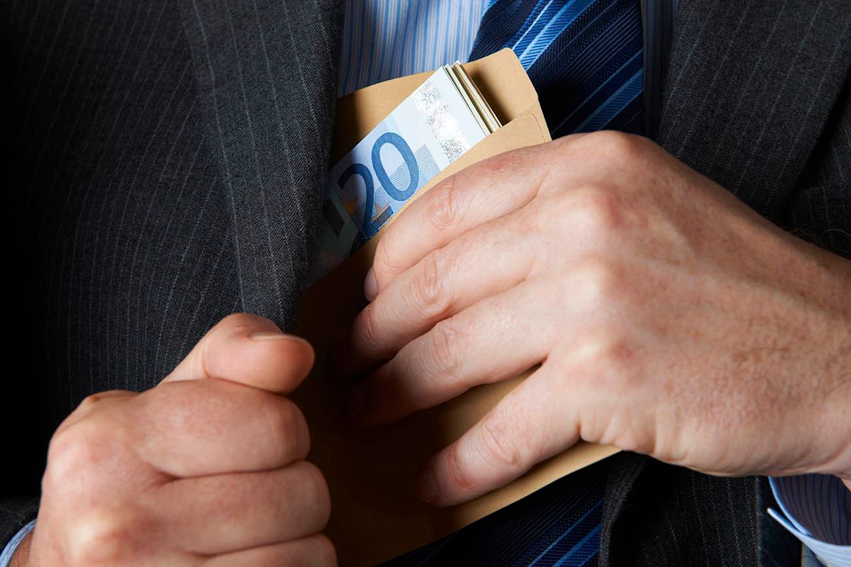 Businessman Putting Envelope Of Euros Into Jacket Pocket
Image depicting corporate greed and corruption