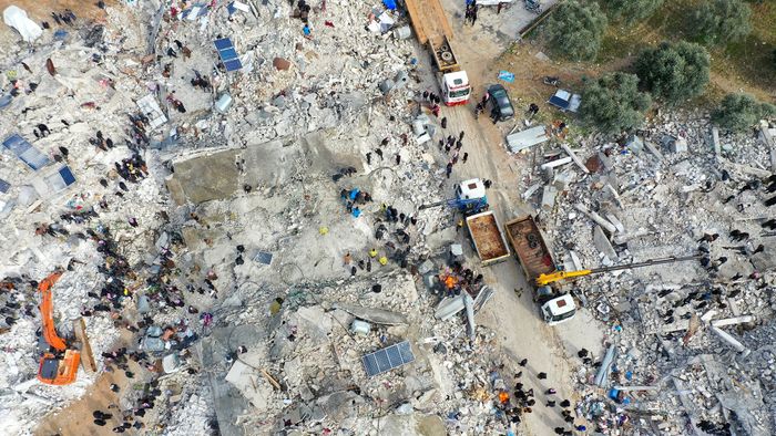 This aerial view shows residents searching for victims and survivors amidst the rubble of collapsed buildings following an earthquake in the village of Besnia near the twon of Harim, in Syria's rebel-held noryhwestern Idlib province on the border with Turkey, on February 6, 2022. - Hundreds have been reportedly killed in north Syria after a 7.8-magnitude earthquake that originated in Turkey and was felt across neighbouring countries. (Photo by Omar HAJ KADOUR / AFP)