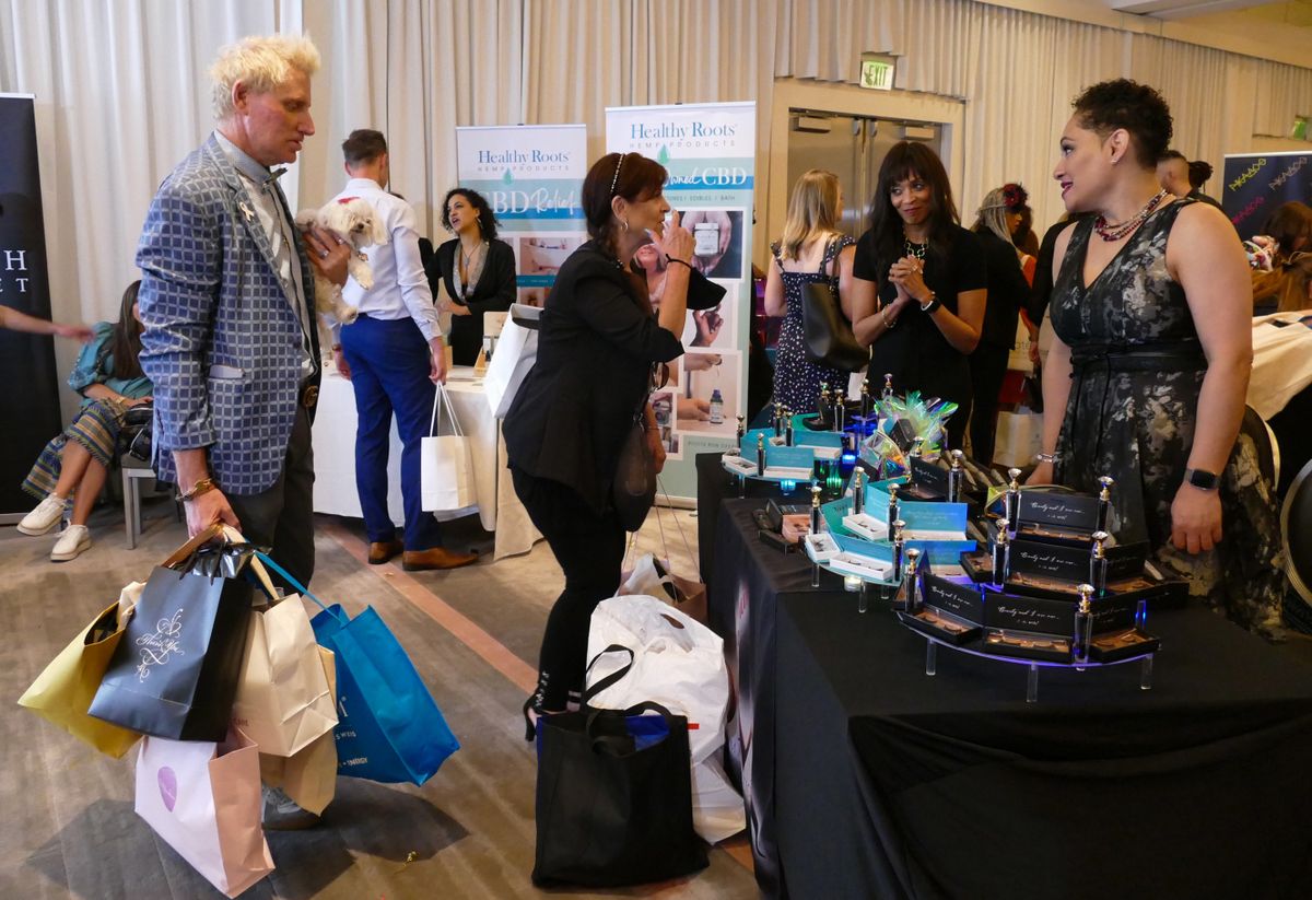 25 March 2022, US, Los Angeles: Patrik Simpson (l, TV personality from the show "Gown and Out in Beverly Hills" lines up for gifts with pooch SnowWhite90210 in a so-called swag suite ahead of the Oscars. (to ""Free stuff" before the Oscars - hemp cosmetics in the gift bag")
