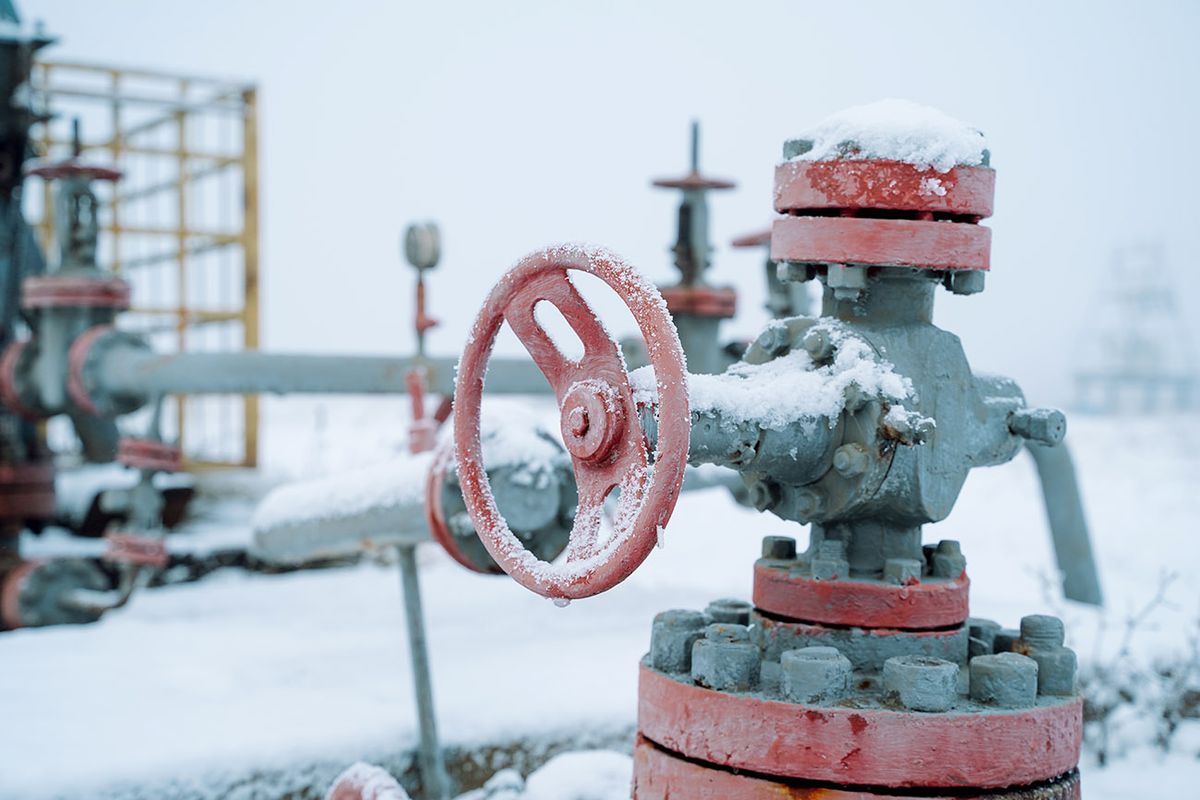 Gasoline shortage, energy crisis in cold season. Control of transportation and transmission of oil and gas in winter Close up of frozen snowy faucet valve on pipe tube in oil and gas field