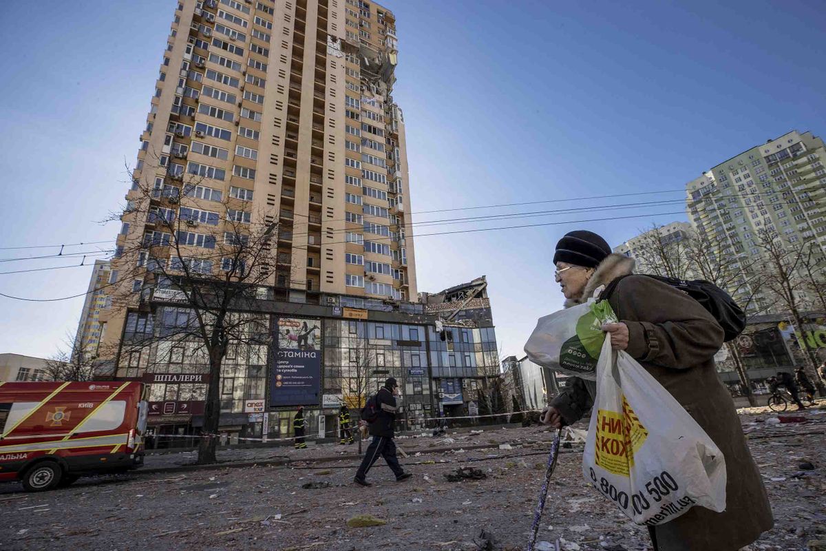 KYIV, UKRAINE - (ARCHIVE): A file photo dated February 28, 2022 shows an elderly woman carrying bags walks past a damaged building with her walking stick after curfew temporarily lifted amid Russian attacks in Kyiv, Ukraine. One year has passed since the start of Russia's war with Ukraine. Aytac Unal / Anadolu Agency 