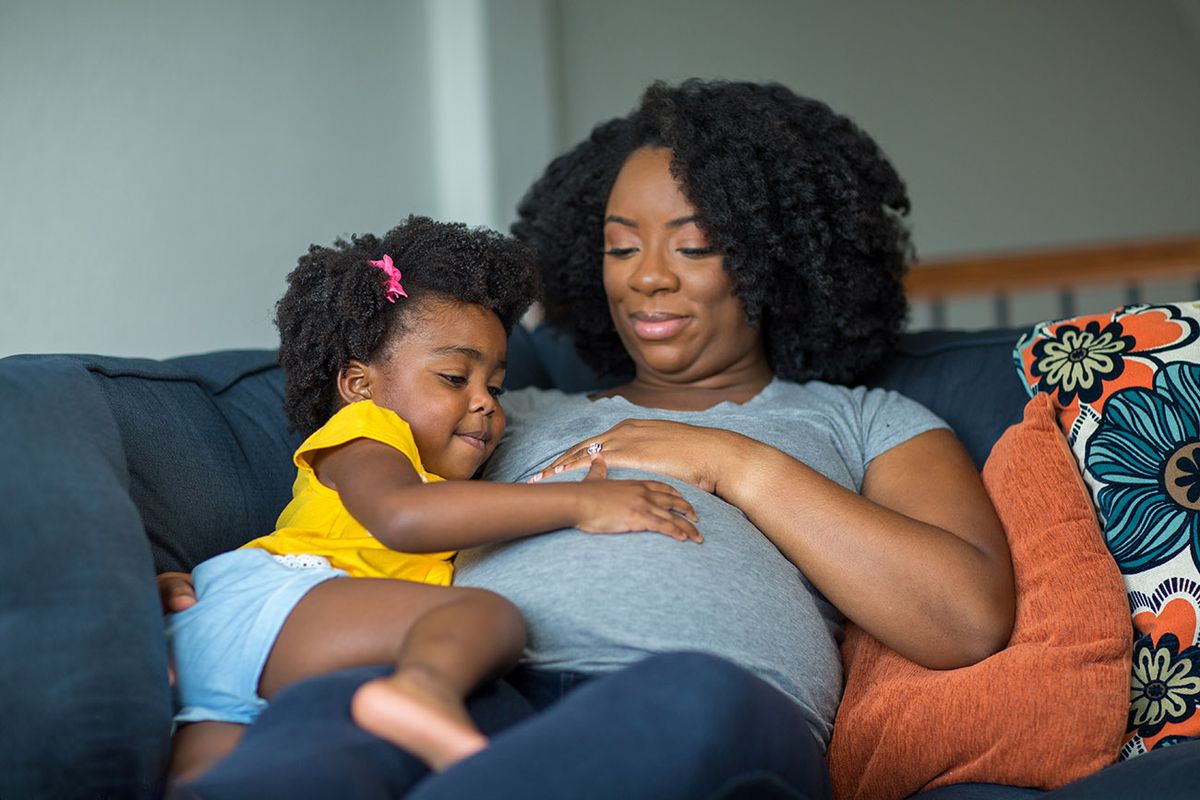 African American pregnant mother and her daughter.
African American mother and daughter smiling at home.