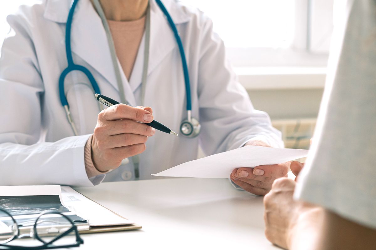 Unrecognizable doctor consulting patient. Giving piece of paper with instructions and recommendations Unrecognizable female doctor consulting patient. Giving instructions and recommendations. Medical symptom diagnostic. Questioning about treatment. Clinical reception