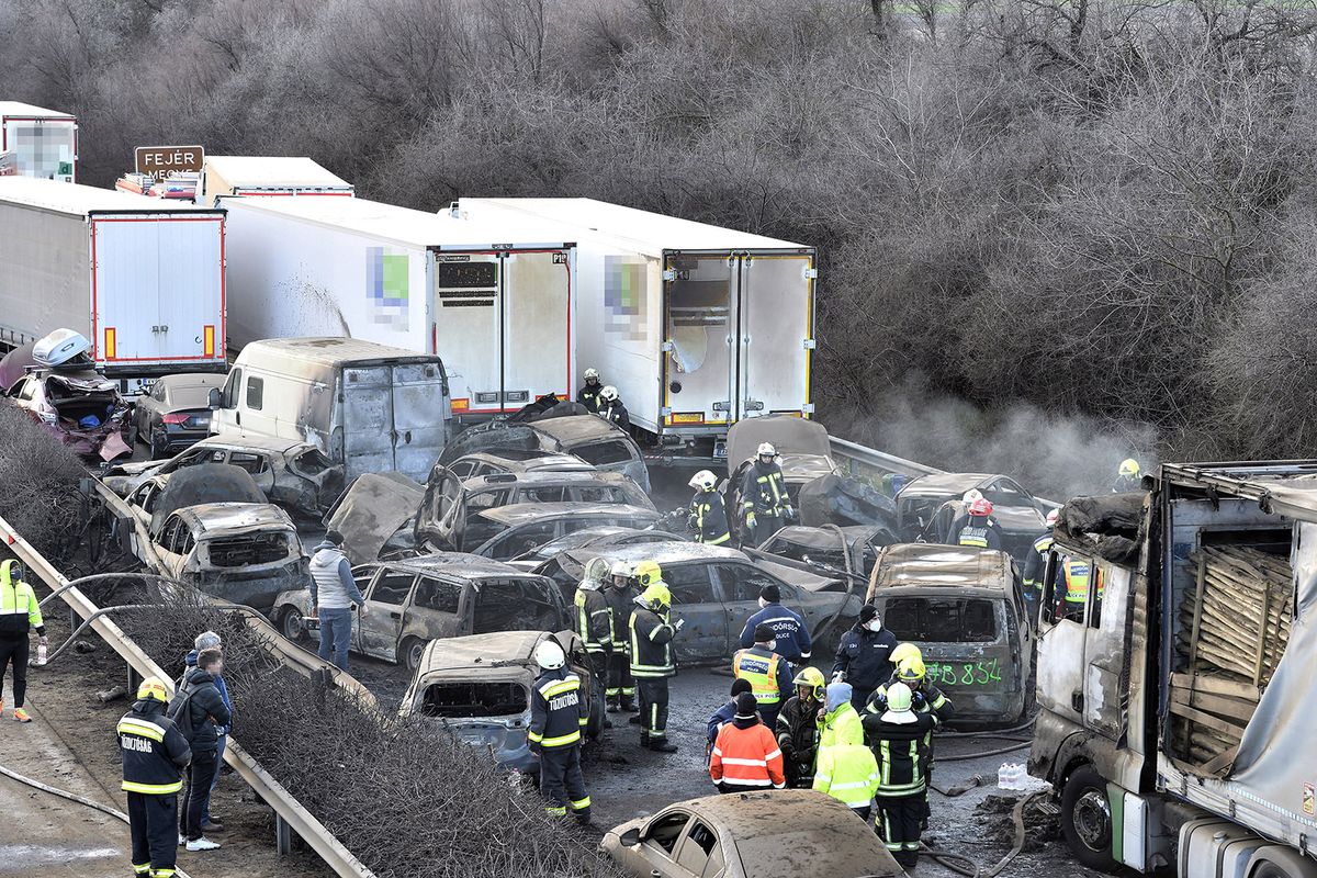 Herceghalom, 2023. március 11.Kiégett és sérült gépjárművek az M1-es autópályán Herceghalomnál, ahol öt kamion és 37 autó ütközött össze, mindkét irányban lezárták az autópályát 2023. március 11-én. A balesetben érintett öt kamion és 37 személygépkocsi közül 19 jármű kiégett, és összesen 26 ember sérült meg. Közülük hatan életveszélyesen, heten pedig súlyosan sérültek.MTI/Lakatos PéterHerceghalom, 2023. március 11.
Kiégett és sérült gépjárművek az M1-es autópályán Herceghalomnál, ahol öt kamion és 37 autó ütközött össze, mindkét irányban lezárták az autópályát 2023. március 11-én. A balesetben érintett öt kamion és 37 személygépkocsi közül 19 jármű kiégett, és összesen 26 ember sérült meg. Közülük hatan életveszélyesen, heten pedig súlyosan sérültek.
MTI/Lakatos Péter
