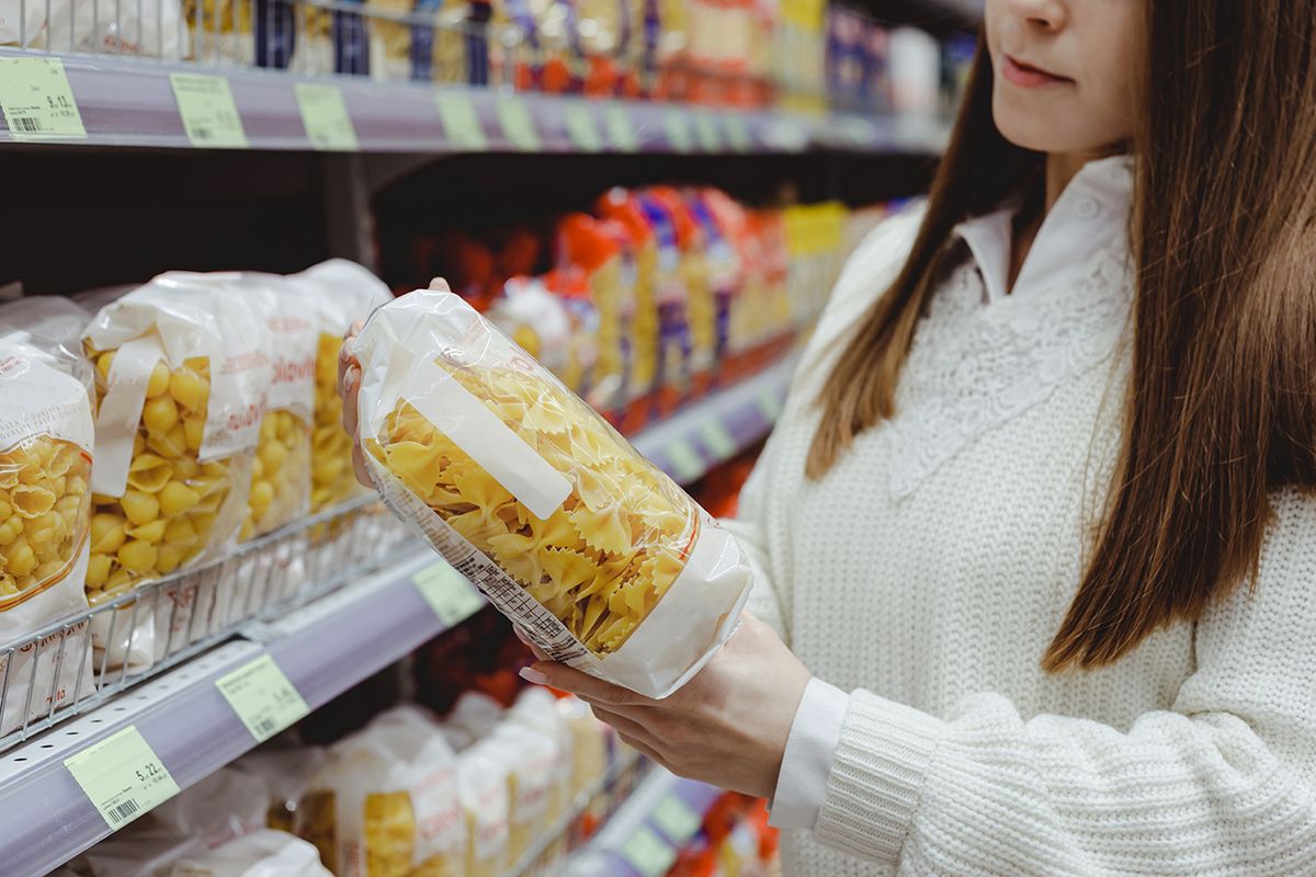 Young,Woman,Holds,Pasta,Package,,Shopping,In,Grocery,Store. Young woman holds pasta package, shopping in grocery store.