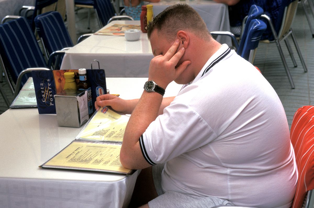 Obese young man at restaurant table