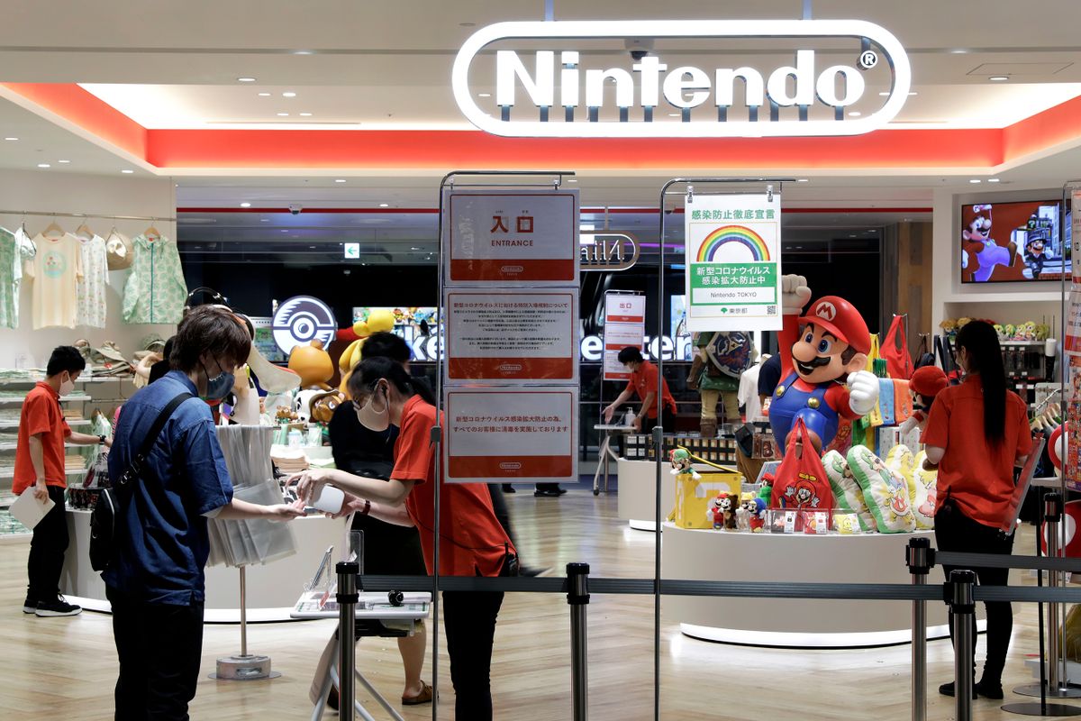 A visitor, second from left, receives hand sanitizer from a store attendant at the entrance of the Nintendo TOKYO store in Tokyo, Japan, on Tuesday, Aug. 4, 2020. Nintendo is scheduled to report first-quarter earnings figures on Aug. 6. 