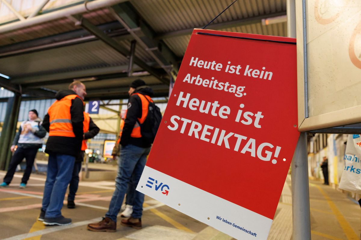 27 March 2023, Baden-Württemberg, Stuttgart: A sign "Today is not a working day" hangs at a strike rally of the EVG at Stuttgart main station. Today is strike day!". Strikers stand in the background and talk. With a large-scale nationwide warning strike, the EVG and Verdi unions paralyzed large parts of public transport on Monday. Photo: Julian Rettig/dpa 