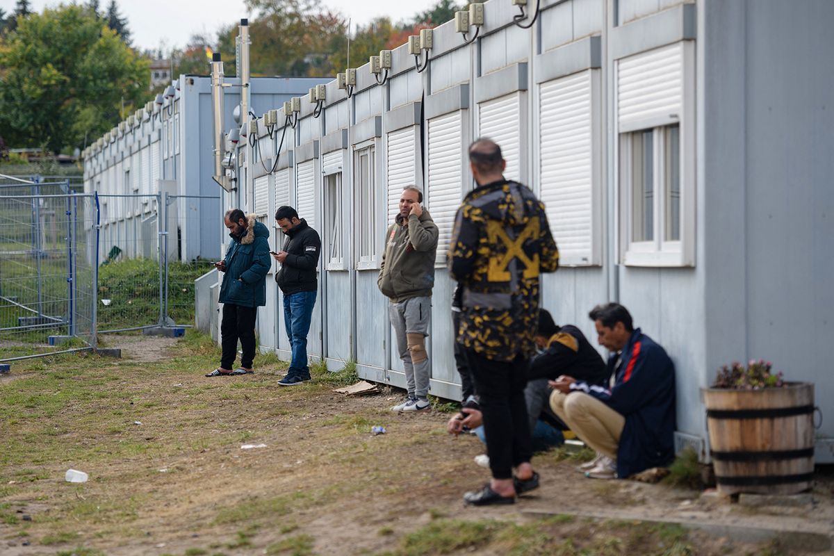 Refugees are seen on the grounds of the arrival centre of the initial reception facility of the eastern German state of Brandenburg in Eisenhuettenstadt, on October 25, 2021. - A recent surge in people crossing illegally over the EU's eastern frontier with Belarus has placed major strains on member states. According to figures from the German interior ministry, around 5,700 people have travelled over the border between Germany and Poland without an entry permit since the start of the year. (Photo by JENS SCHLUETER / AFP)