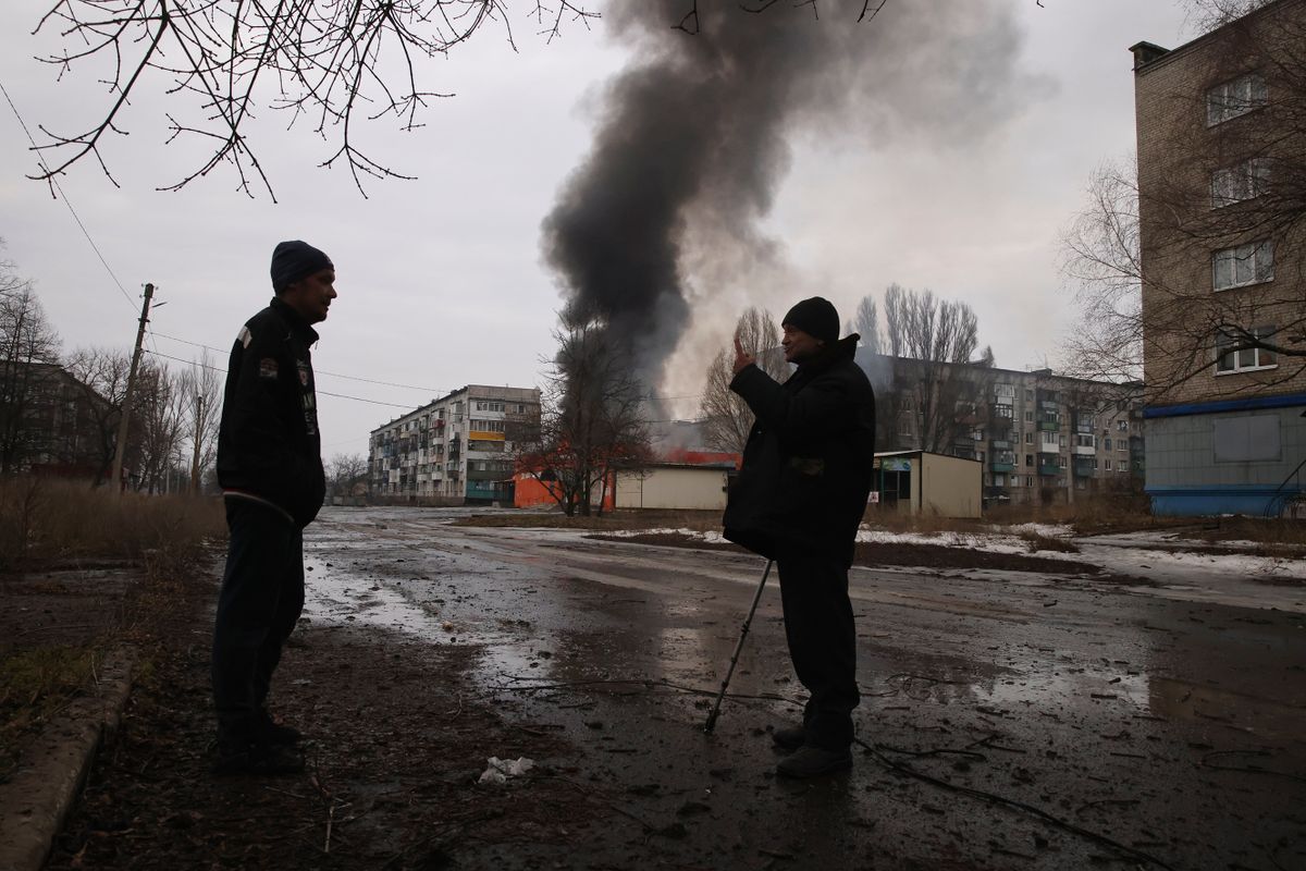 Bahmut, 2023. február 28.Égő ház előtt beszélget két férfi a kelet-ukrajnai Donyecki területen fekvő, az orosz hadsereg által ostromlott Bahmutban 2023. február 27-én.