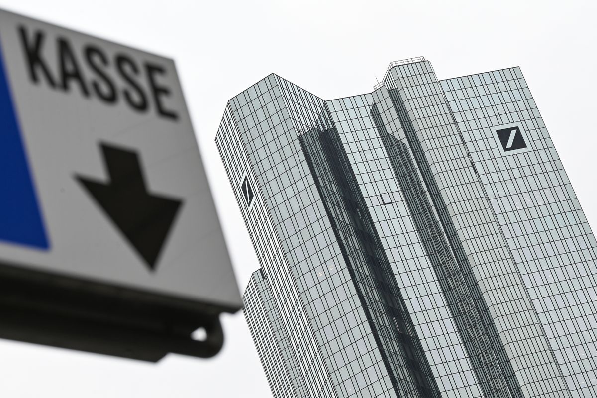 PRODUCTION - 31 January 2023, Hesse, Frankfurt/Main: Behind a sign reading "Kasse" (cash register), Deutsche Bank's head office rises into the air. On February 2, 2023, Germany's largest commercial bank presents its balance sheet for the past financial year.