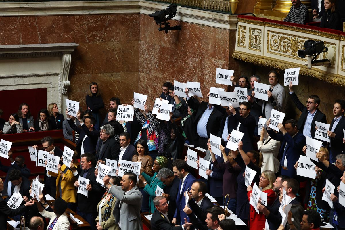 PARIS, FRANCE - MARCH 16: Members of Parliament of left-wing coalition NUPES (New People's Ecologic and Social Union) hold placards as French Prime Minister Elisabeth Borne addresses deputies to confirm the force through of the pension law without a parliament vote during a session at the French National Assembly on March 16, 2023 in Paris, France. Today, the French Government pushed their Pension Reform, which has sparked a waves of protests and strikes, through parliament without a vote after enacting article 49.3 of the constitution.  