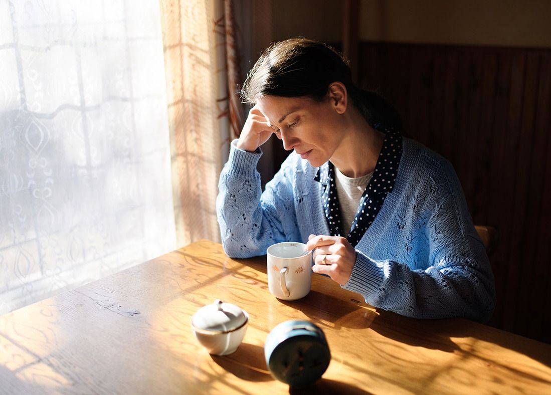 Portrait of unhappy poor mature woman indoors at home, poverty concept. Portrait of unhappy poor mature woman with coffee indoors at home, poverty concept.