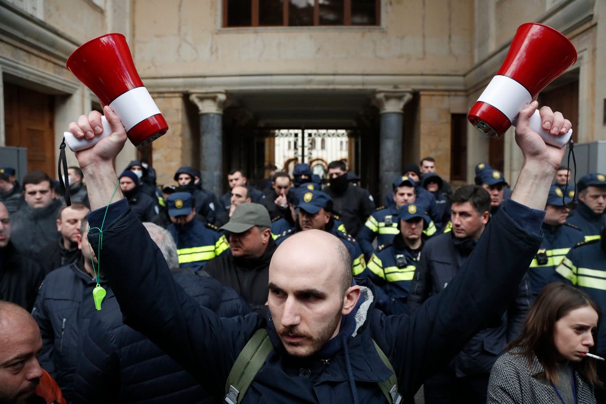 Tbiliszi, 2023. március 8.Rohamrendőrök felé megy egy georgiai zászlót viselő tüntető a külföldi ügynökökről szóló törvény elleni tiltakozáson Tbilisziben 2023. március 7-én, miután a parlament első olvasatban elfogadta a jogszabályt. A kormányzó Georgiai Álom párt által támogatott törvény előírja, hogy a működési költsége több mint egyötötdét külföldi forrásból biztosító szervezet „külföldi ügynökként” regisztráltassa magát az igazságügyi minisztériumban, ellenkező esetben súlyos bírsággal sújtják. Szalome Zurabisvili államfő közölte, hogy támogatja a tüntetőket.MTI/AP/Zurab Tsertsvadze, Szalome