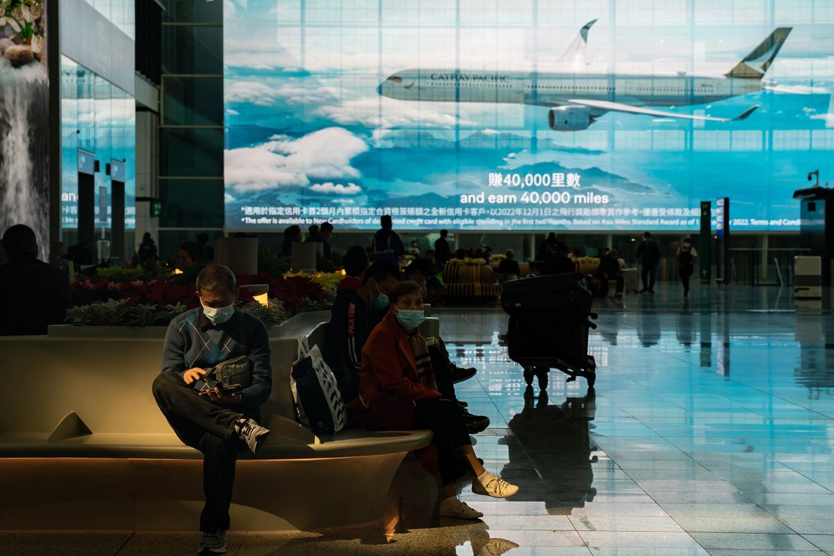 HONG KONG, CHINA - DECEMBER 30: Travellers sit at the arrival hall of the Hong Kong International Airport on December 30, 2022 in Hong Kong, China. Authorities around the world are imposing or considering curbs on travellers from China as COVID-19 case there surge following its relaxation of Zero-COVID rules. 