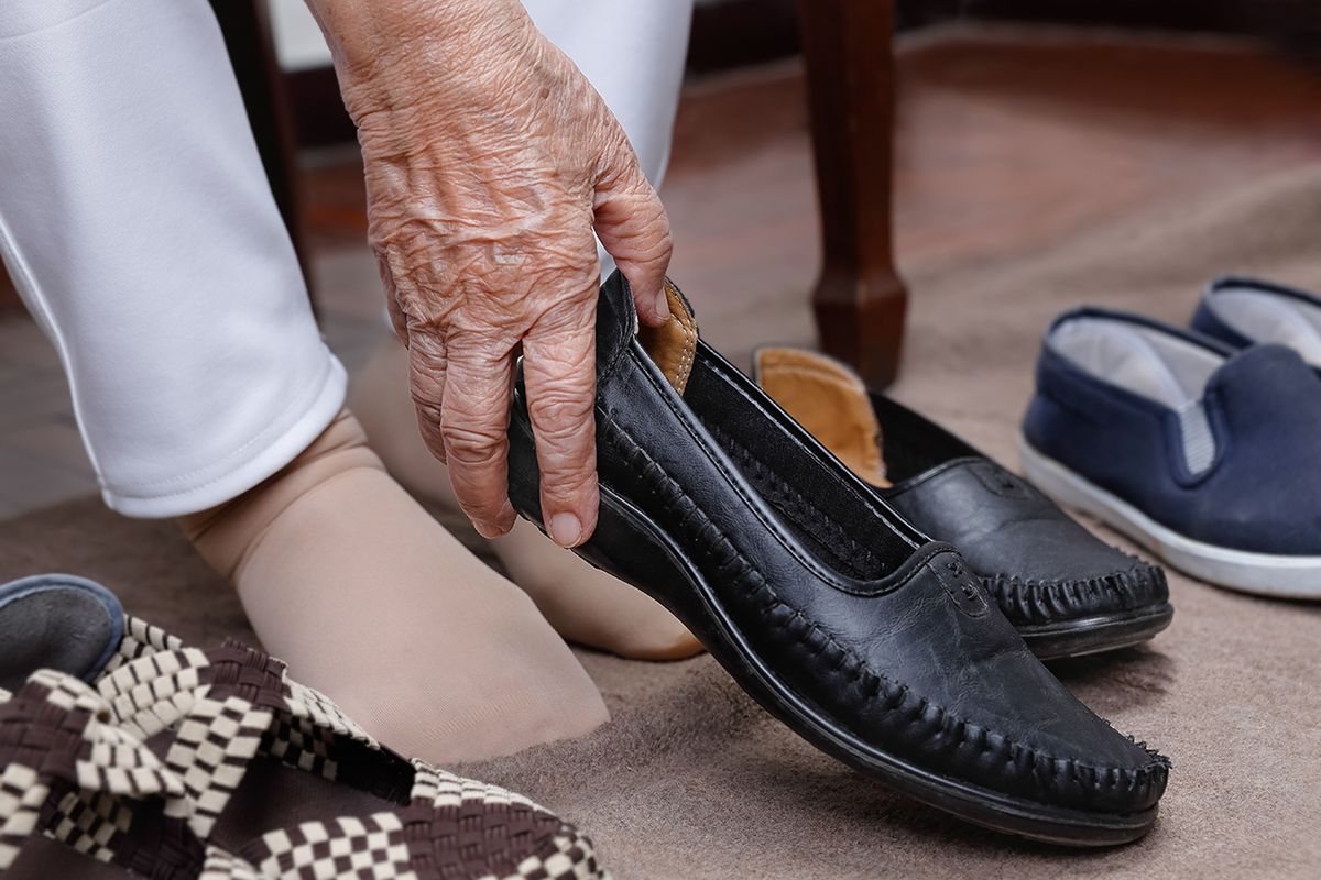 Elderly,Woman,Swollen,Feet,Putting,On,Shoes,At,Home. Elderly woman swollen feet putting on shoes at home.