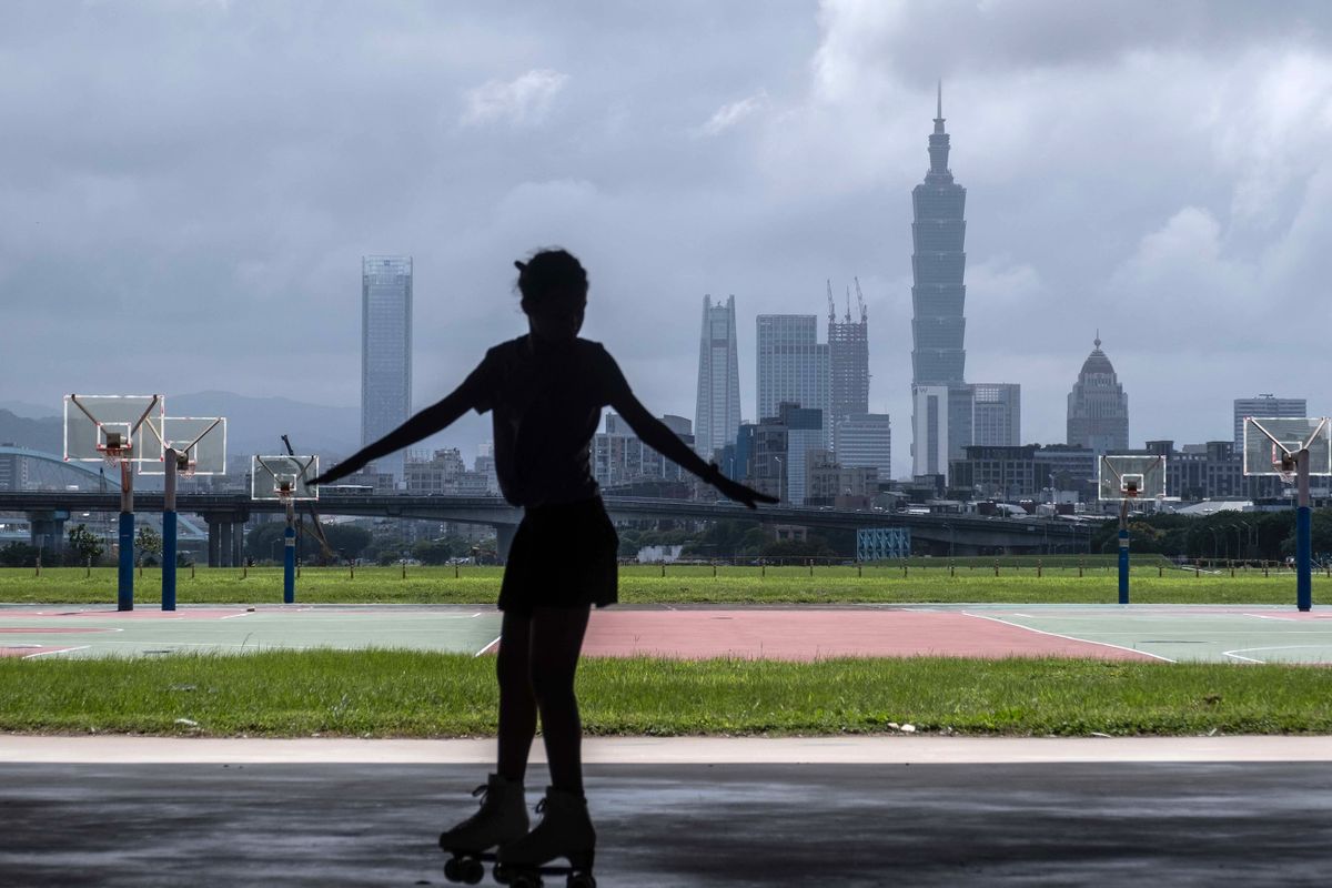 A woman roller skates in front of the Taipei skyline in Taoyuan, Taiwan, on Wednesday, Oct. 5, 2022. Taiwan warned it would treat any Chinese incursion into the island's airspace as a "first strike," as Taipei seeks to deter Beijing from ratcheting up military pressure around the island. 