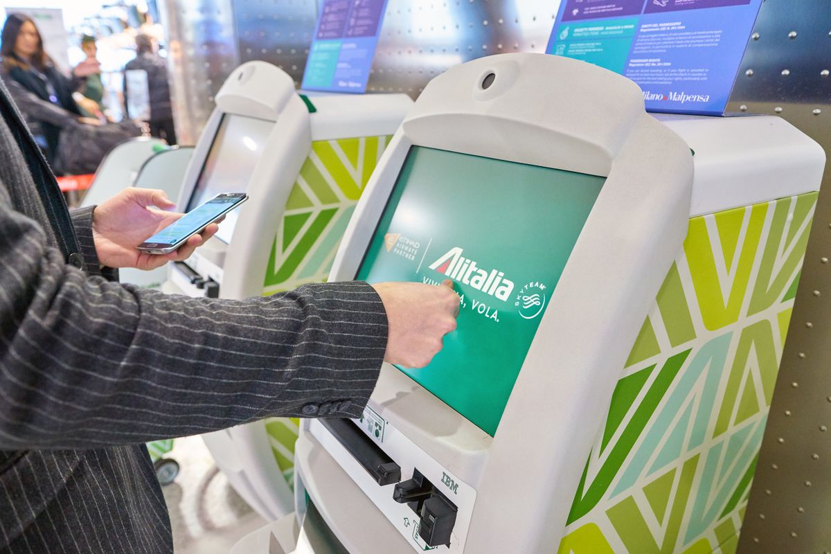 Milan Malpensa, Italy - Circa November 2017: A passenger uses Alitalia self-check-in kiosks at Milan Malpensa Airport, Terminal 1. 