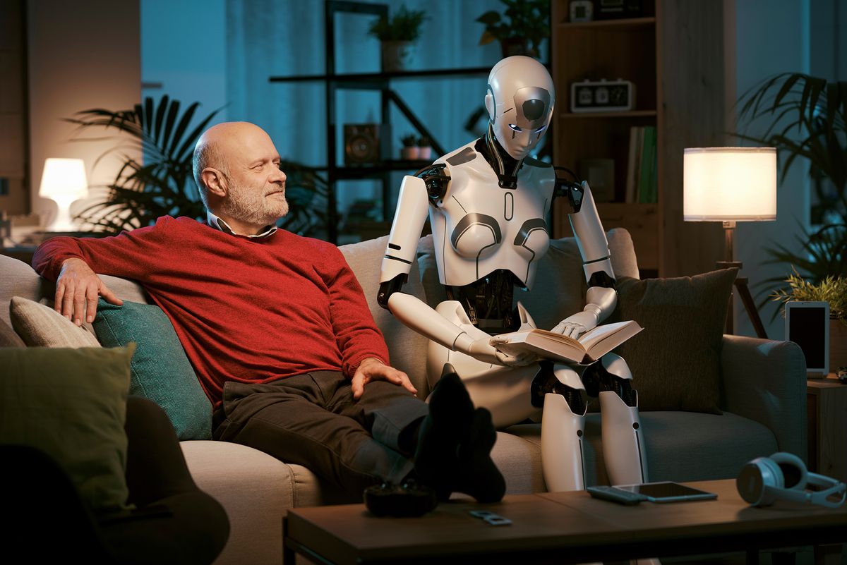 Senior,Man,And,Female,Android,Robot,Sitting,On,The,Couch