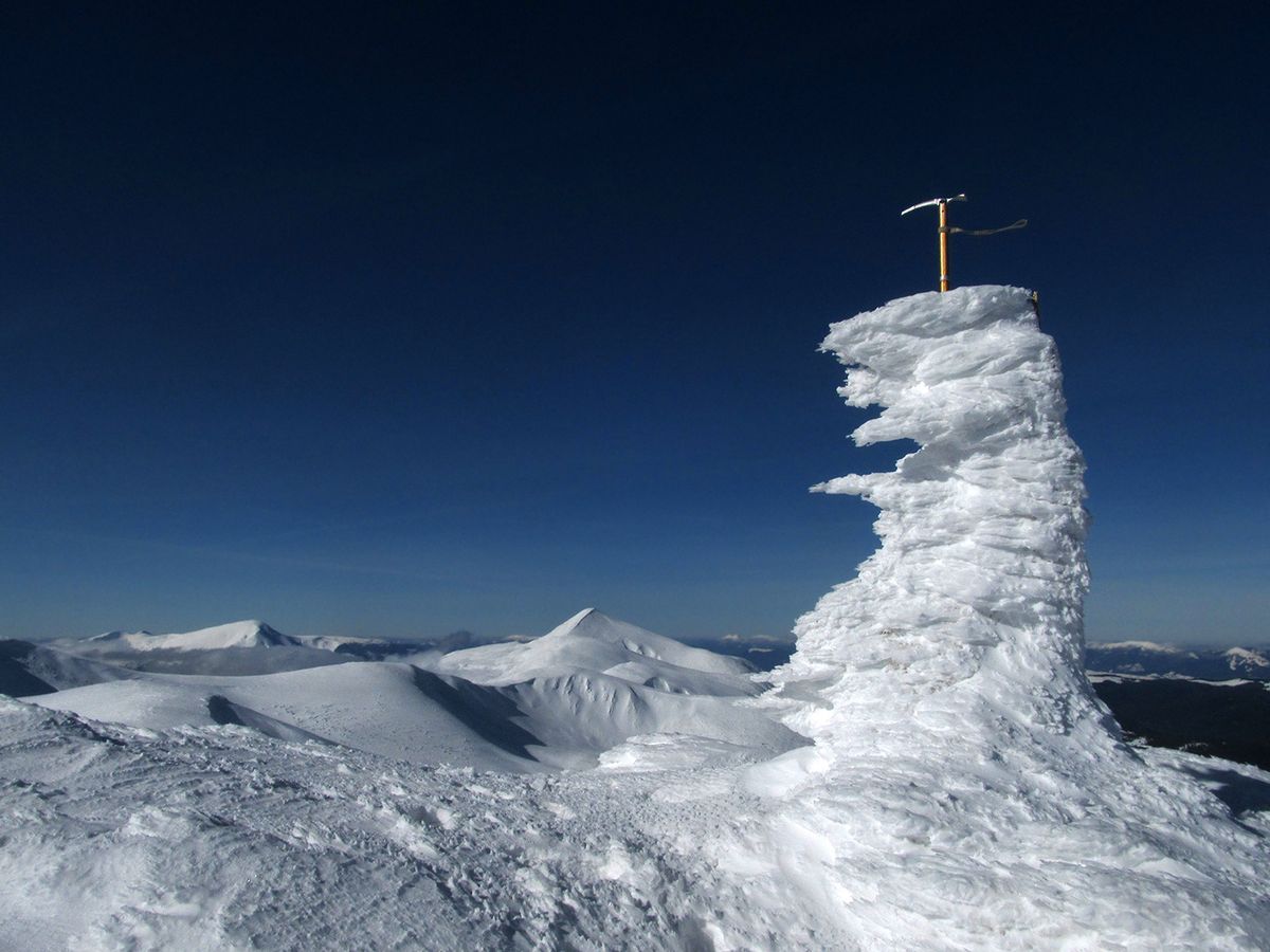 Ice,Axe,Stucking,In,The,Snow,On,The,Top,Of
Ice axe stucking in the snow on the top of mountain. Snow-covered peaks in winter. View of Mount Hoverla, Chornohora ridge, Carpathians, Ukraine. 