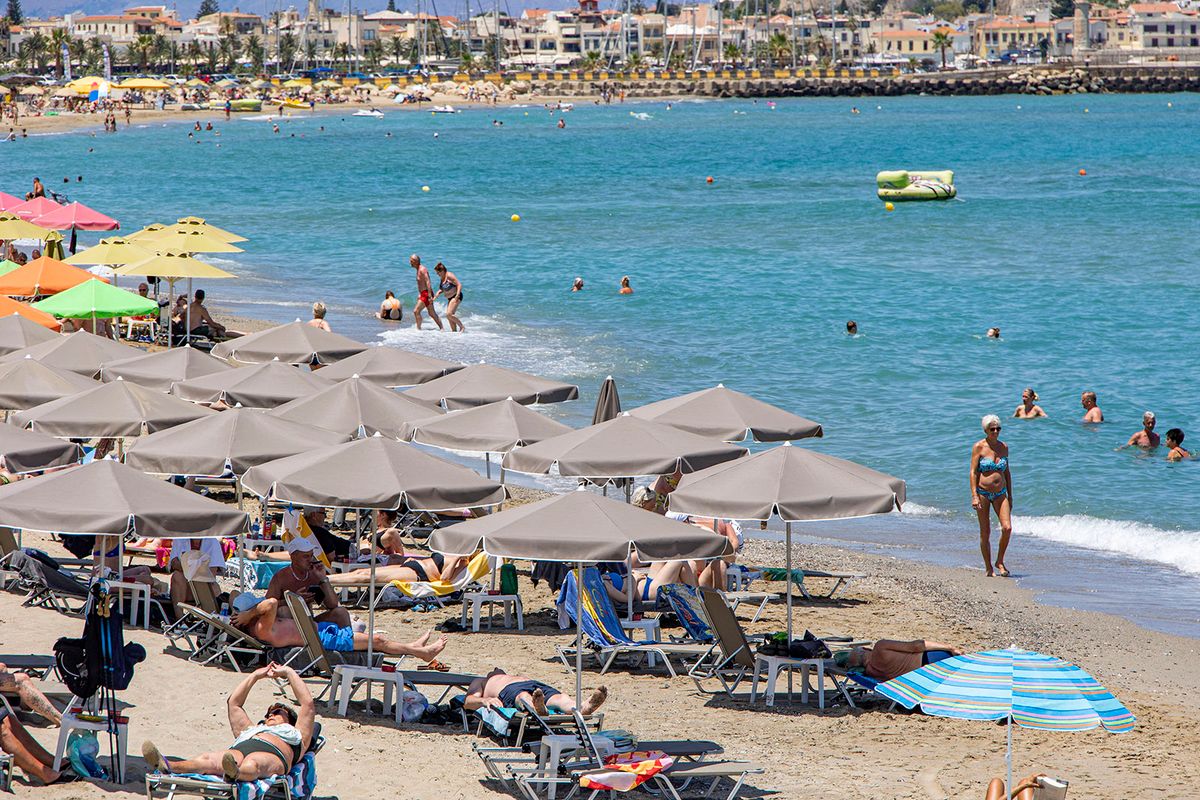 Tourism In Greece - Beach Life Of Rethymno Coast In Crete Island
Tourism in Greece. The coast of Rethymno town with the long sandy beach and the beach bars in Creta island with the mountains in the background. People are seen tanning while wearing bathing suit, swimsuit, bikini, enjoying the sun under the umbrella at the beach bar on a sun bed, and swimming in the crystal clear sea. Rethymno is a historic Mediterranean beach town on the northern coast of Crete, laying on the Aegean Sea with a population of 40.000 people. A touristic destination with a historic Venetian port and town, archaeological sites, endless sandy beaches, watersports, nice beautiful traditional taverns, and a big variety of hotels. Tourism is bouncing back with reservations exceeding the pre-pandemic numbers, putting Greece and the Greek islands on high demand. Tourists travel after the Covid-19 Coronavirus pandemic. Rethimno, Crete island, Greece on June 13, 2022 (Photo by Nicolas Economou/NurPhoto) (Photo by Nicolas Economou / NurPhoto / NurPhoto via AFP)