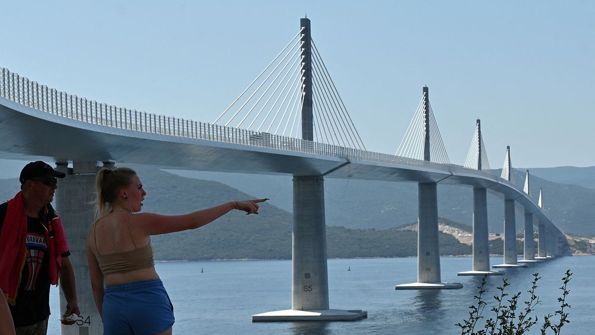 CROATIA-BOSNIA-EU-TRANSPORT-BRIDGE
Croatian 1991-95 war veteran Ivan Petrinjak (62) (L), from Northern-Croatian city of Varazdin, who travelled with his 2 daughters, 2 sons and a grand son, looks at the newly built Peljesac Bridge, a cable-stayed bridge in Dubrovnik-Neretva County spanning the sea channel between Komarna on the northern mainland and the peninsula of Peljesac, on July 26, 2022 ahead of the official opening ceremony scheduled on July 29. - The bridge connects central and southern parts of Croatian Adriatic coast, via Peljesac peninsula. The bridge linking Peljesac peninsula with the Croatian mainland has been widely regarded as one of the country's most ambitious infrastructure projects since Zagreb declared independence from Yugoslavia in 1991. (Photo by ELVIS BARUKCIC / AFP)