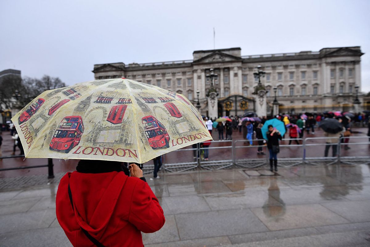 A woman shelters from the rain under an umbrella following the Changing of the Guard ceremony at Buckingham Palace in London on January 16, 2017. - Prime Minister Theresa May won endorsement from US President-elect Donald Trump over her Brexit course but sterling plunged on Monday on fears that Britain could be on a collision course with its EU allies. (Photo by BEN STANSALL / AFP)