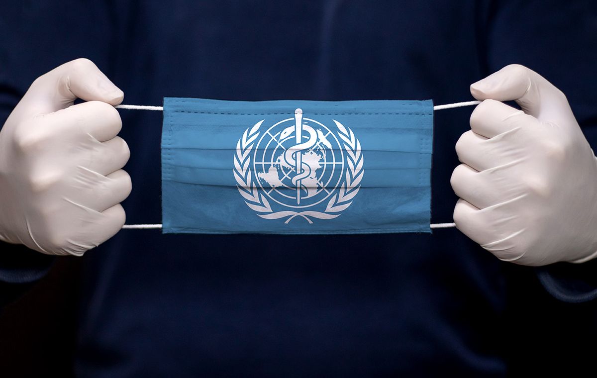 Health,Employee,Doctor,Holding,Medical,Face,Mask,With,Who,(world Health employee doctor holding medical face mask with WHO (World Health Organization) flag. Coronavirus (COVID-19) pandemic affects the country. 