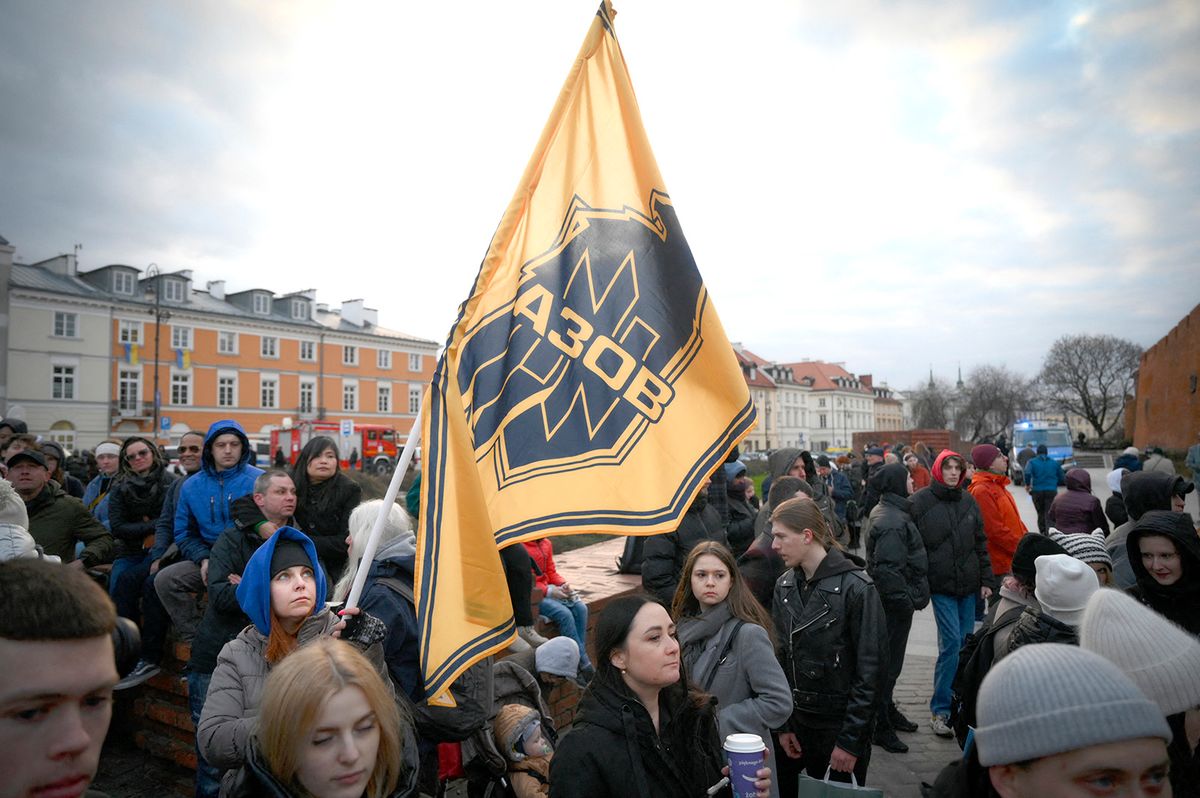 Poland Pledges More Jets To Ukraine As Zelensky Meets Po lish Leaders In Warsaw 
A woman waves an Azov Assault Brigade flag as hundreds gather to see Volodymyr Zelensky speak at the Royal Castle in Warsaw, Poland on 05 April, 2023. Ukrainian President Volodymyr Zelensky is visiting Poland on Wednesday to meet with his Polish counterpart Andrzej Duda and make a public appearance meeting with Ukrainian and Polish citizens in Warsaw. (Photo by Jaap Arriens/NurPhoto) (Photo by Jaap Arriens / NurPhoto / NurPhoto via AFP)