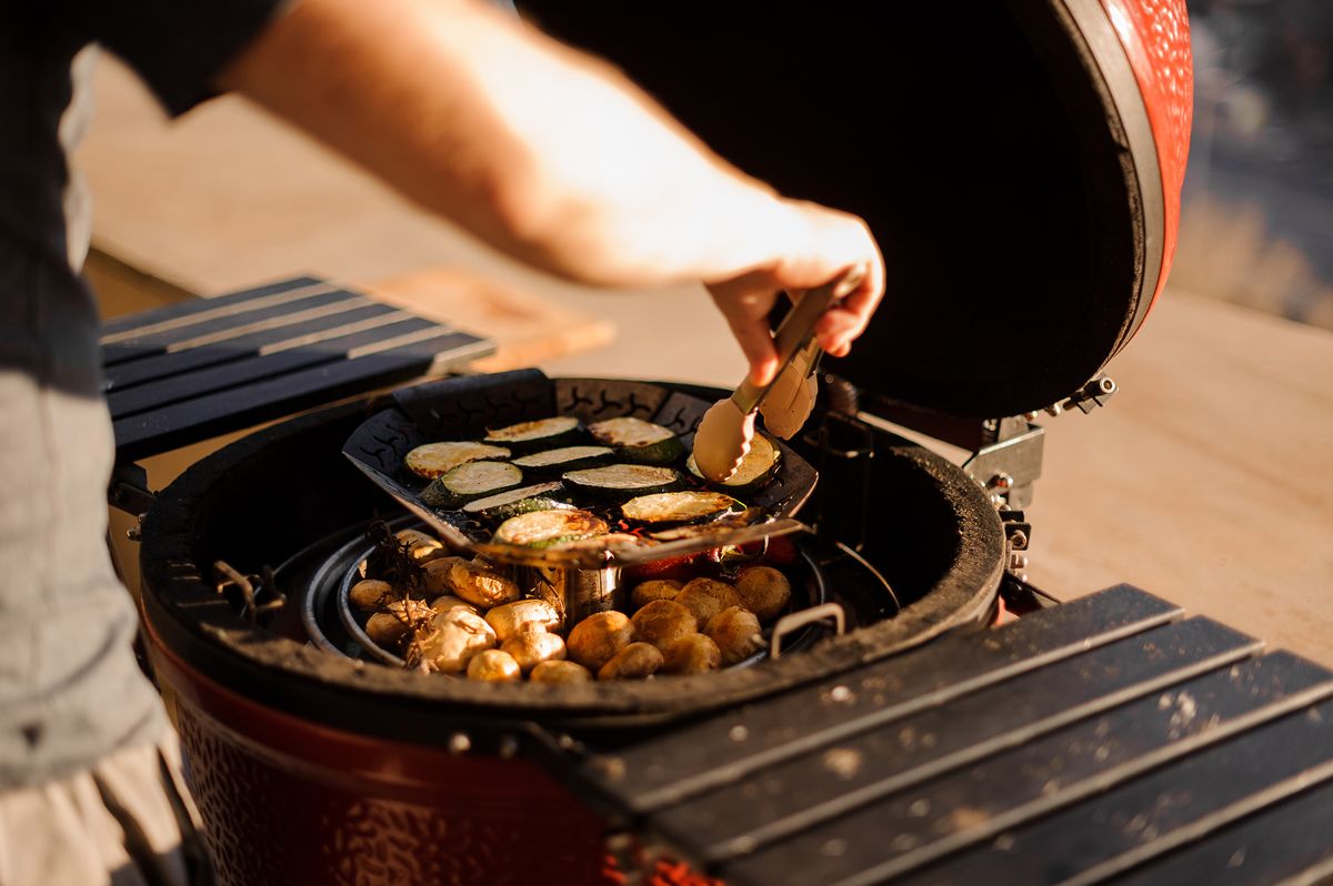 Man cooking red peppers, mushrooms and egg-plants on the grill