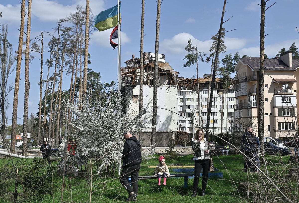 Local residents wander as workers dismantle a heavily damaged residential building in the town of Irpin, Kiev, on April 19, 2023, amid the Russian invasion of Ukraine. (Photo by Genya SAVILOV / AFP)
