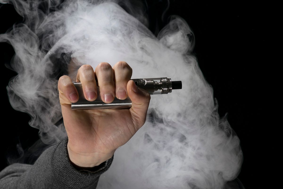 Young person vaping an e cig with lots of clouds. Isolated on a dark background.
Isolated young man on a black background holding an electronic cigarette, vaping device, mod, e-cig.