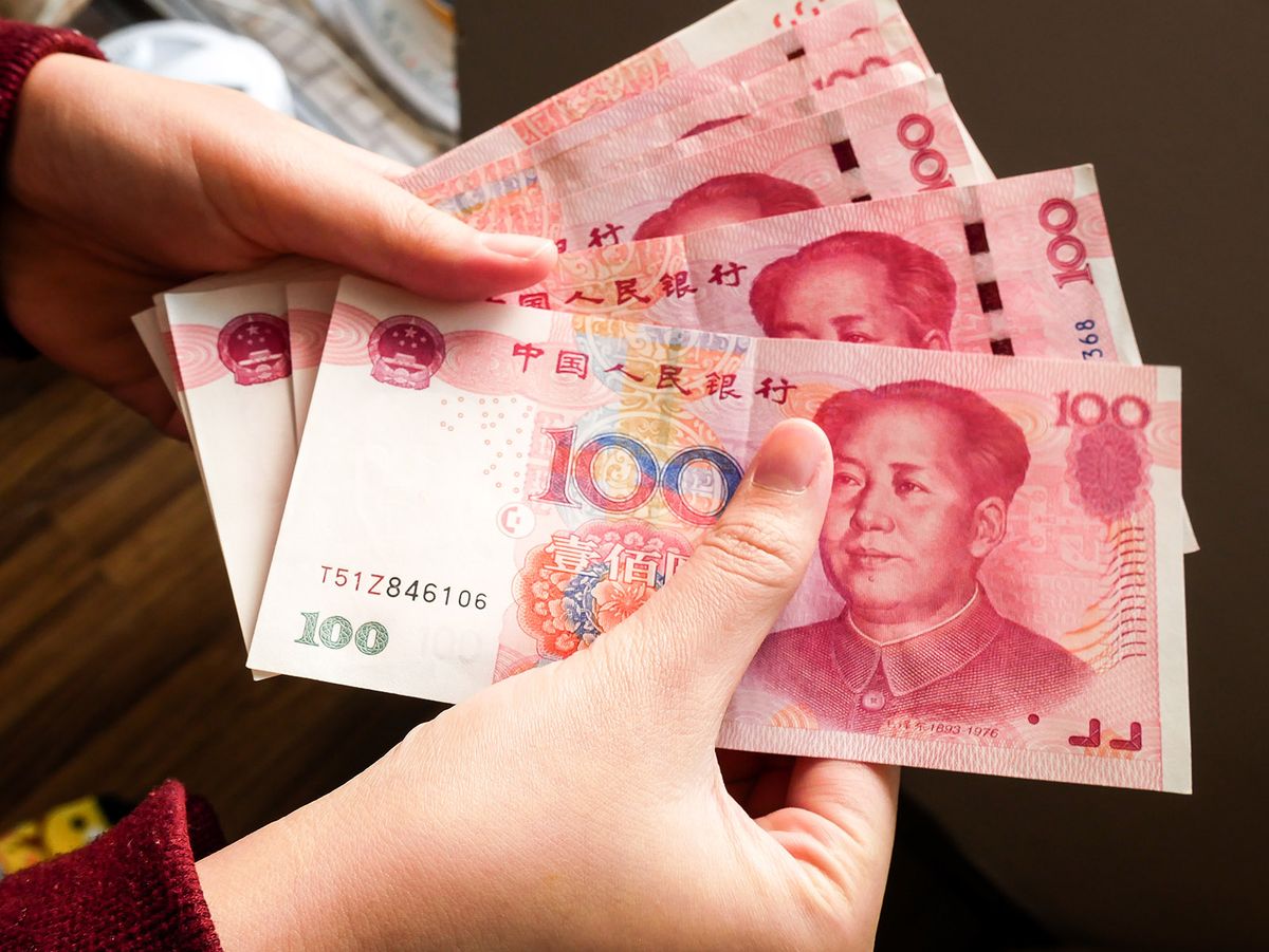 A,Pile,Of,100,Rmb,Banknotes,Of,Chinese,Yuan,Money A pile of 100 RMB banknotes of Chinese yuan money in a female hand exchanging for travel.