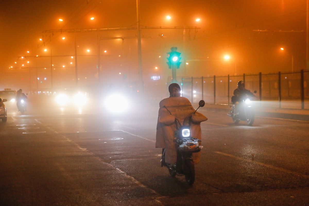 Peking, 2023. április 10.Homokvihar miatt arcmaszkot viselő motorosok Pekingben  2023. április 10-én.