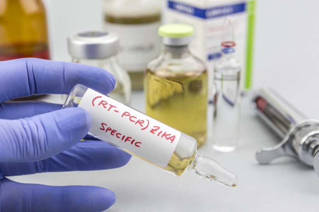 Blue latex gloved hands holding vials of ZIKA virus