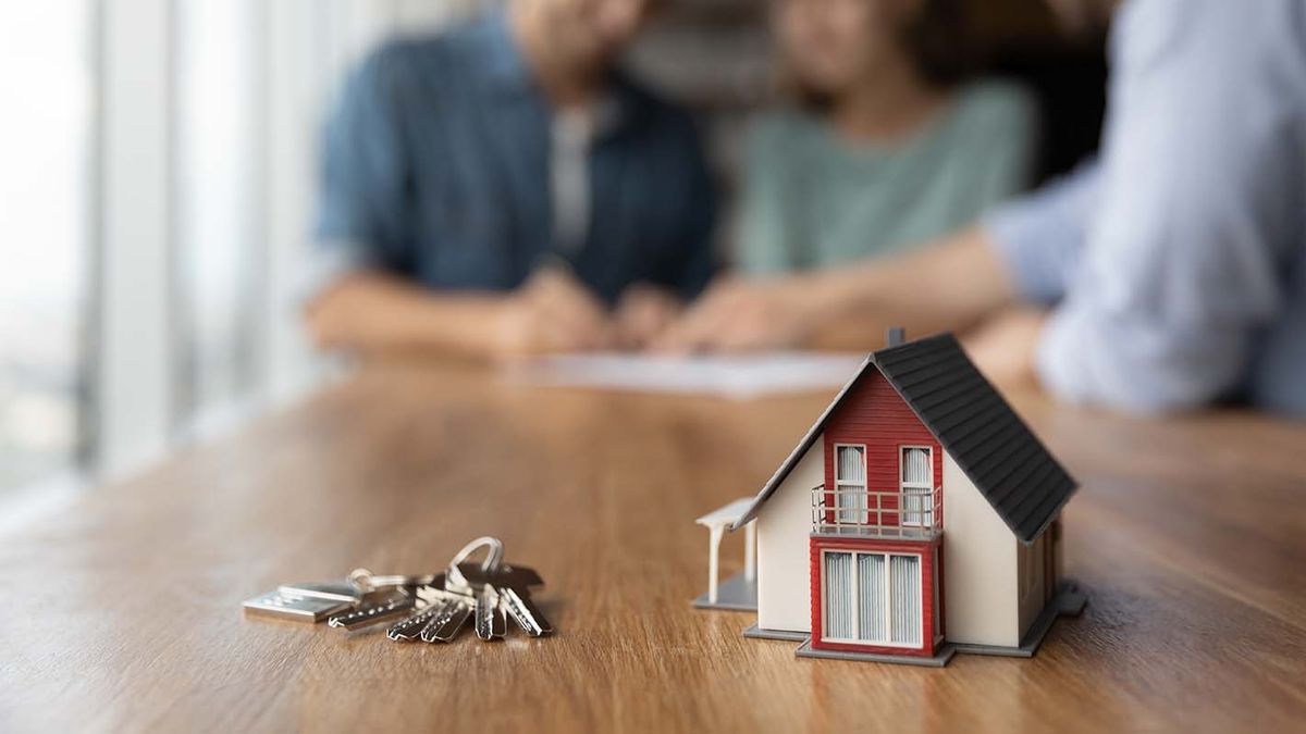 Close,Up,Of,Key,And,Tiny,Toy,House,On,Table.
Close up of key and tiny toy house on table. Married couple buying house, consulting, lawyer, legal advisor, real estate agent, bank manager, signing mortgage agreement in background
