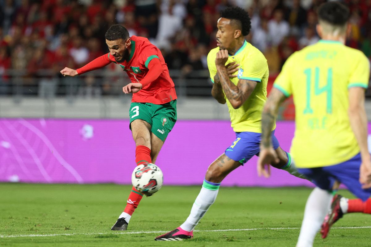 Morocco's defender Noussair Mazraoui (L) attempts a shot during a friendly football match between Morocco and Brazil at the Ibn Batouta Stadium in Tangier on March 26, 2023. (Photo by  / AFP)