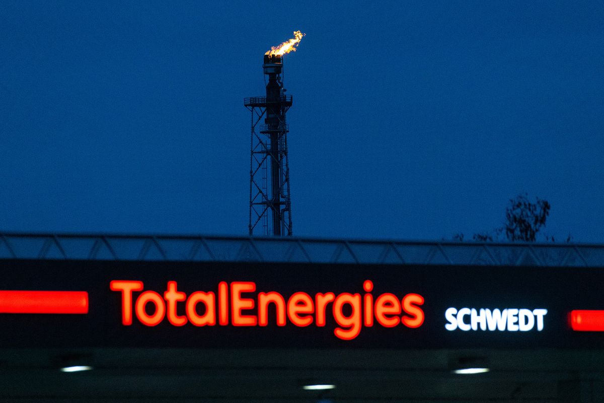 Fire burns from a flare stack at the PCK Schwedt oil refinery, formerly owned by Rosneft PJSC and now controlled by the German government, beyond a TotalEnergies SE gas station in Schwedt, Germany, on Monday, March 20, 2023. Germany's economy will probably shrink in the first quarter of the year, according to the ZEW institute's gauge of expectations, as concerns over risks in the banking sector add to headwinds from inflation, even as the rate should decline "significantly", the Bundesbank said.  