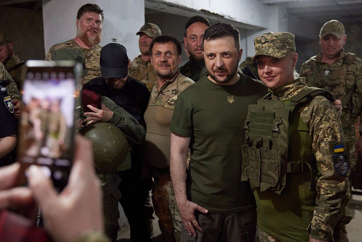 This handout picture taken and released by the press service of the Ukrainian Presidency on 18 June, 2022 shows Ukrainian President Volodymyr Zelensky (2ndR) posing for the picture with a servicewoman during his visit to the position of Ukrainian troops in Mykolaiv region. 