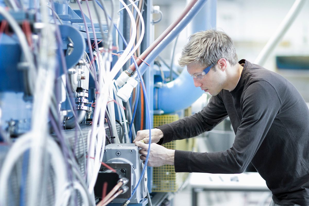 Mid adult male technician maintaining cables in engineering plant