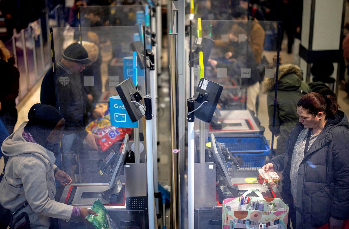 Shoppers use self-scan checkouts as they pay for their grocery shoppings at a Lidl supermarket in Walthamstow, east London on February 13, 2022. - UK annual inflation struck 5.4 percent in December, stoking fears of a cost-of-living squeeze as wages fail to keep pace. (Photo by Tolga Akmen / AFP)