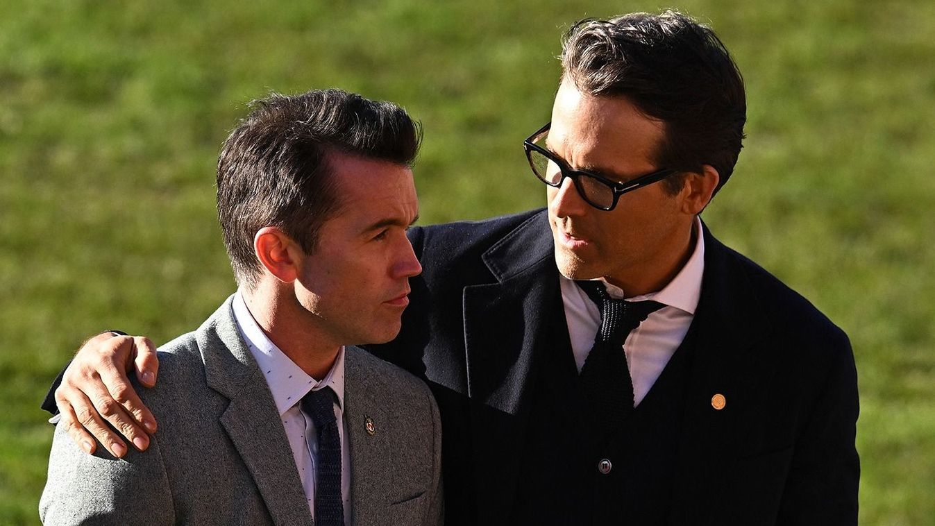 BRITAIN-ROYALS-FBL
Wrexham AFC's Co-Chairmen, US actors Ryan Reynolds (R) and Rob McElhenney wait on the pitch to greet the King and Queen Consort, during their visit to Wrexham Association Football Club in north Wales on December 9, 2022. (Photo by Oli SCARFF / AFP)