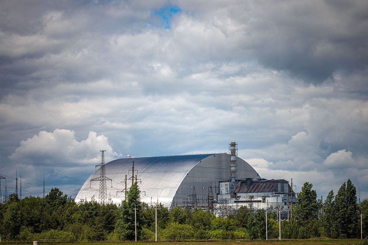 A photograph shows the New Safe Confinement at Chernobyl Nuclear Power Plant which cover the number 4 reactor unit on May 29, 2022, amid the Russian invasion of Ukraine. - More than a 100 employees who had shown up just hours before for their night shift were now trapped as Russian forces crossed into Ukraine and seized swaths of land as they marched toward Kyiv. The capture of the Chernobyl by Russian forces kicked off a weeks-long ordeal that saw power briefly cut at the facility and employees carefully monitored by the invaders as they grappled with fresh uncertainty during the invasion’s early days. (Photo by Dimitar DILKOFF / AFP)