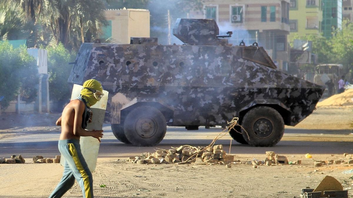 A protester holds a makeshift shield as he stands near a riot police armoured vehicle during an anti-government demonstration in the Sharoni area in the north of Sudan's capital Khartoum on March 14, 2023. (Photo by AFP)
