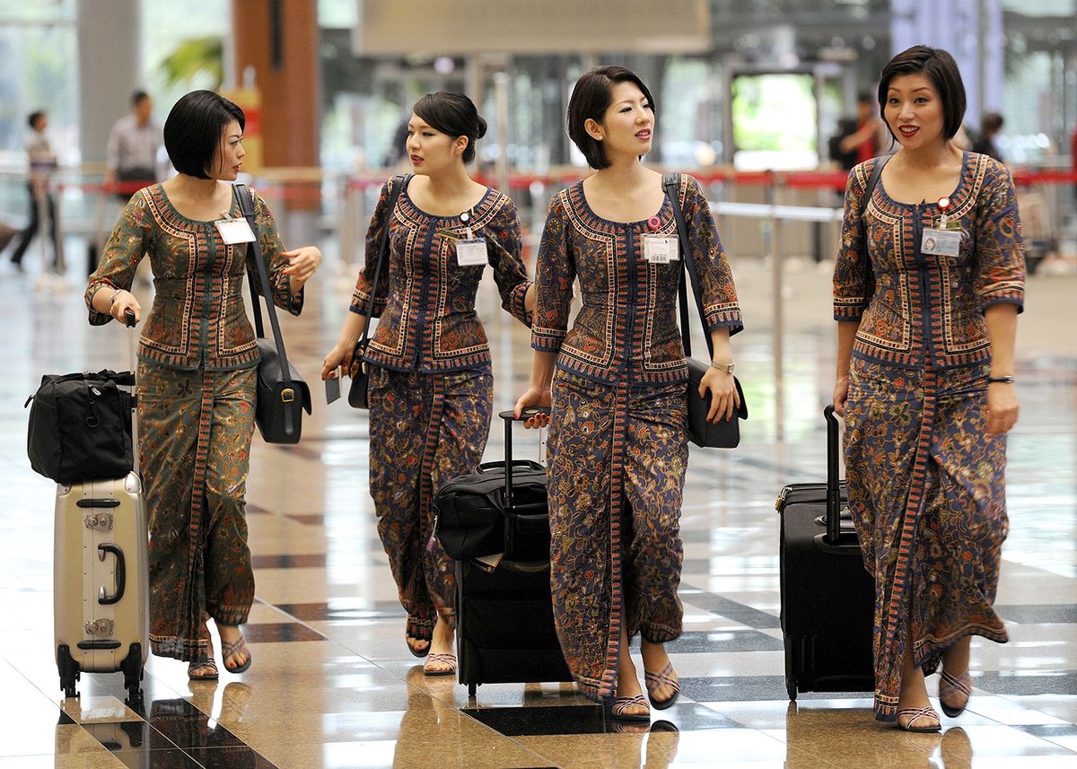 Singapore Airlines Ltd. flight attendants walk through Changi Airport in Singapore, on Wednesday, Oct. 31, 2012. Singapore Air is scheduled to release first-half earnings on Nov. 2. Photographer: Munshi Ahmed/Bloomberg via Getty Images